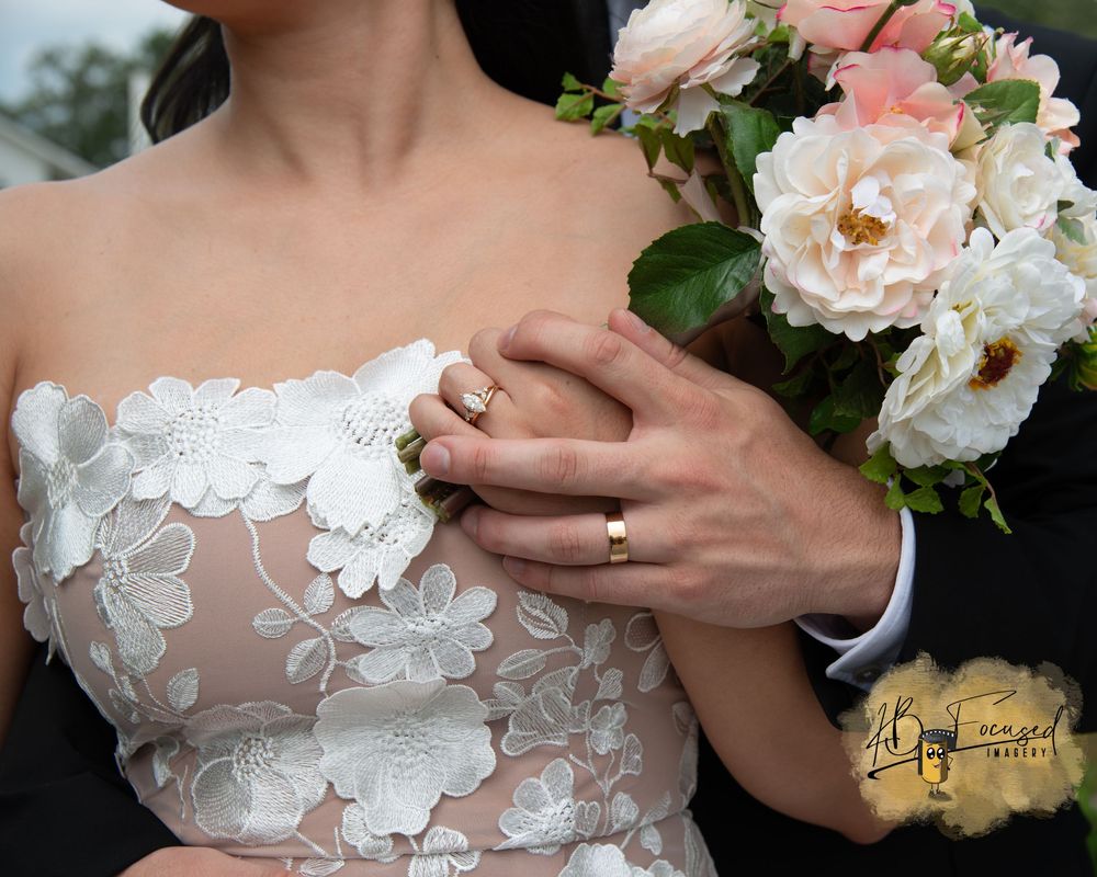 Close-up of delicate floral lace wedding dress details with bouquet.
