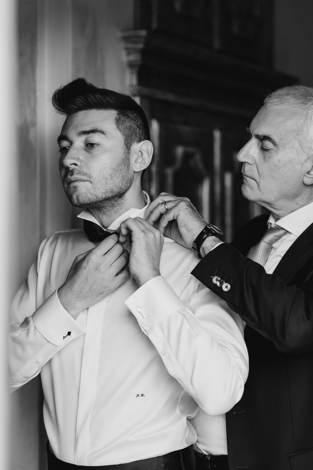 Series of black and white shots showing someone adjusting their collar and tie.