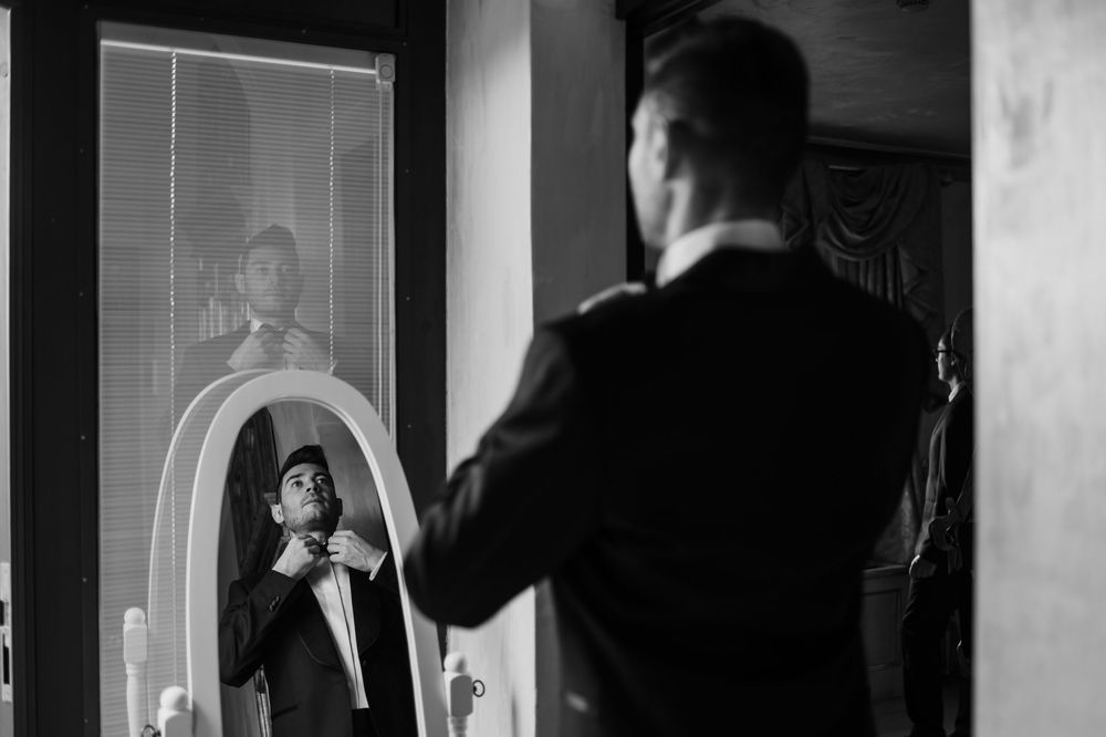 Black and white sequence of someone preparing in front of a mirror.