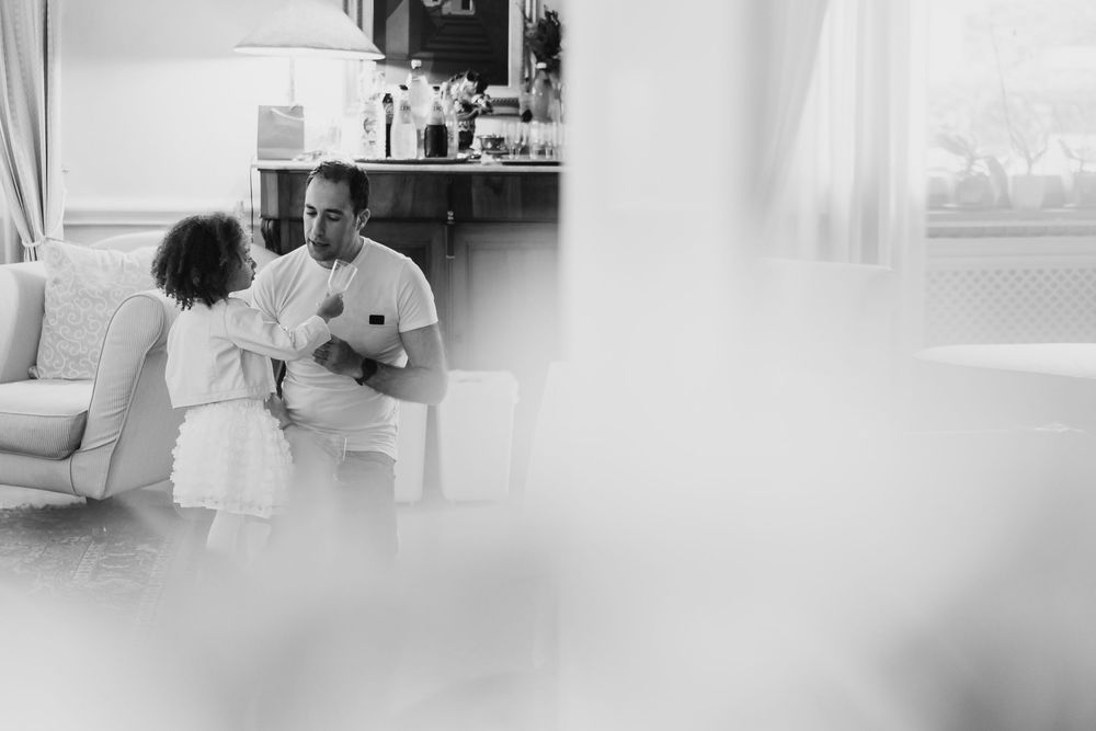 Black and white candid moments captured during wedding preparation in a bright room.