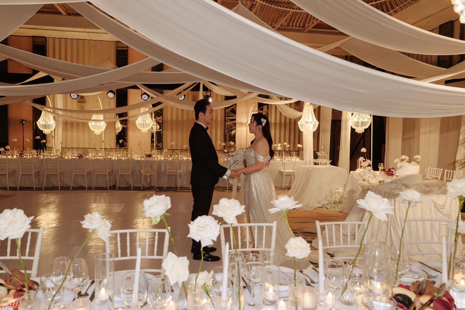 Couple shares a quiet moment on the dance floor of an elegantly decorated wedding ballroom.