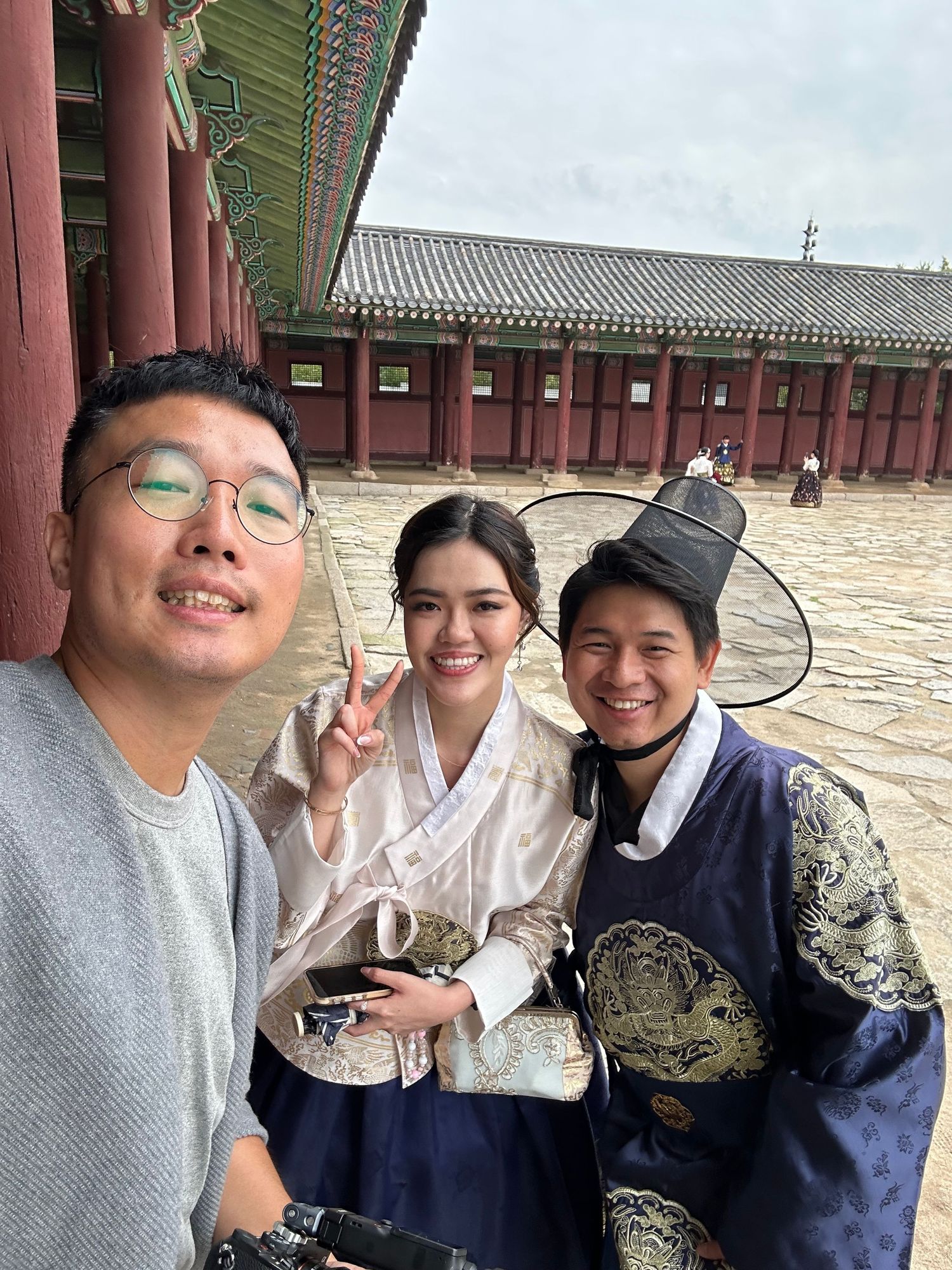 A group poses together in traditional Korean hanbok outfits at Gyeongbokgung Palace's courtyard.