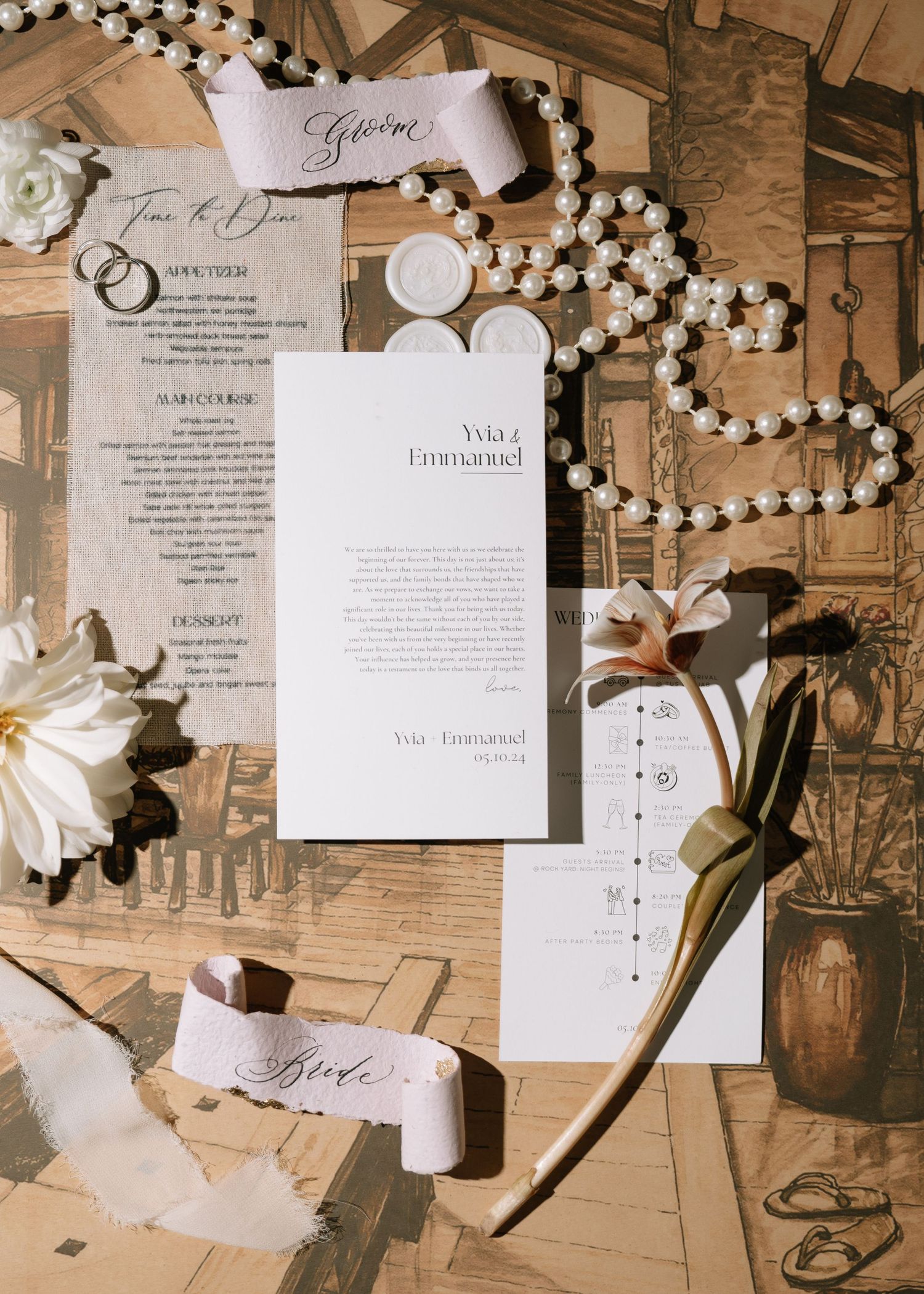 Wedding stationery flatlay with Yvia and Emmanuel program, invitation, and ribbon details.