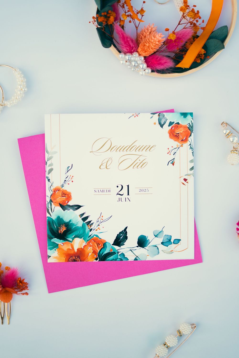 Elegant floral wedding invitation with pink envelope featuring watercolor flowers and gold text.