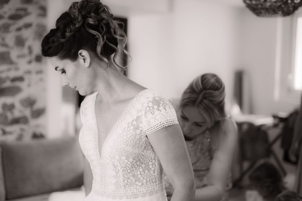A bride in a white lace dress gets ready for her wedding in an elegant dressing room.