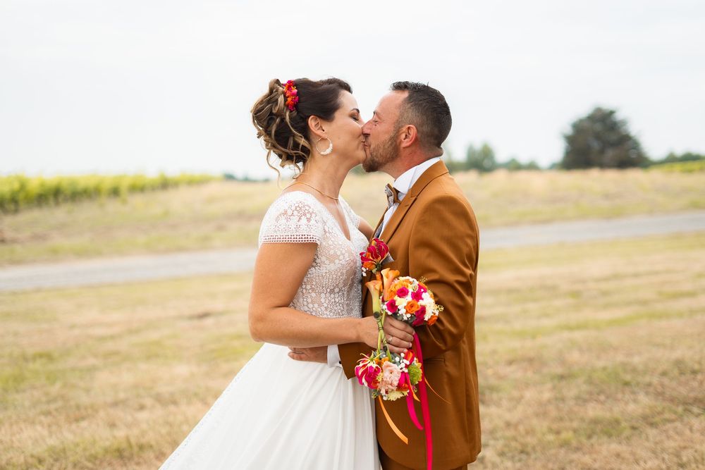 Couple embraces and shares romantic moment in golden sunlit field during outdoor wedding celebration.