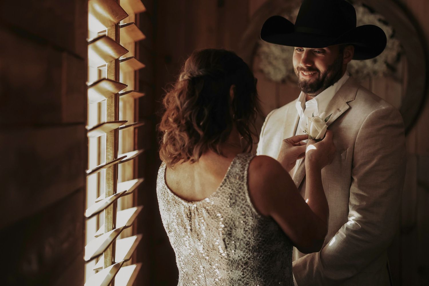 Groom preparing for wedding day with cowboy boots and boutonniere