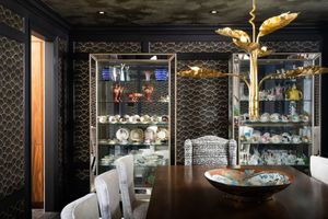 Modern bar interior with dark textured walls, glass display cases, and elegant gold pendant lighting creating an upscale atmosphere.