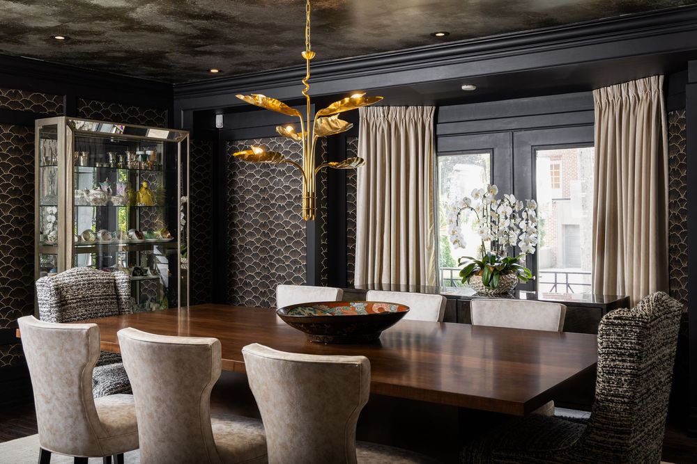 Elegant modern dining room features a long wooden table and upholstered chairs beneath dramatic dark pendant lighting.