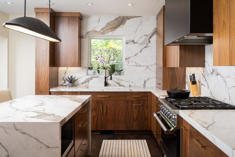 Contemporary kitchen featuring marble backsplash, wood cabinetry, and sleek stainless steel appliances in an open layout design.