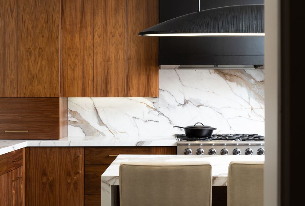 Modern kitchen interior with dark wood cabinets, pendant lighting, and stainless steel appliances.