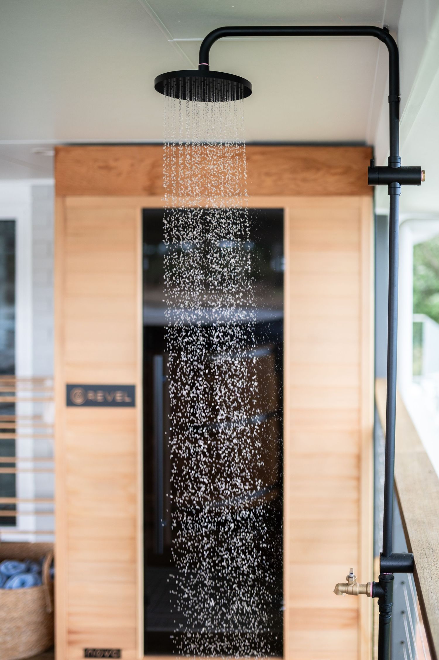 Black rain shower head mounted on light wood wall sprays water streams in six consecutive progression shots.