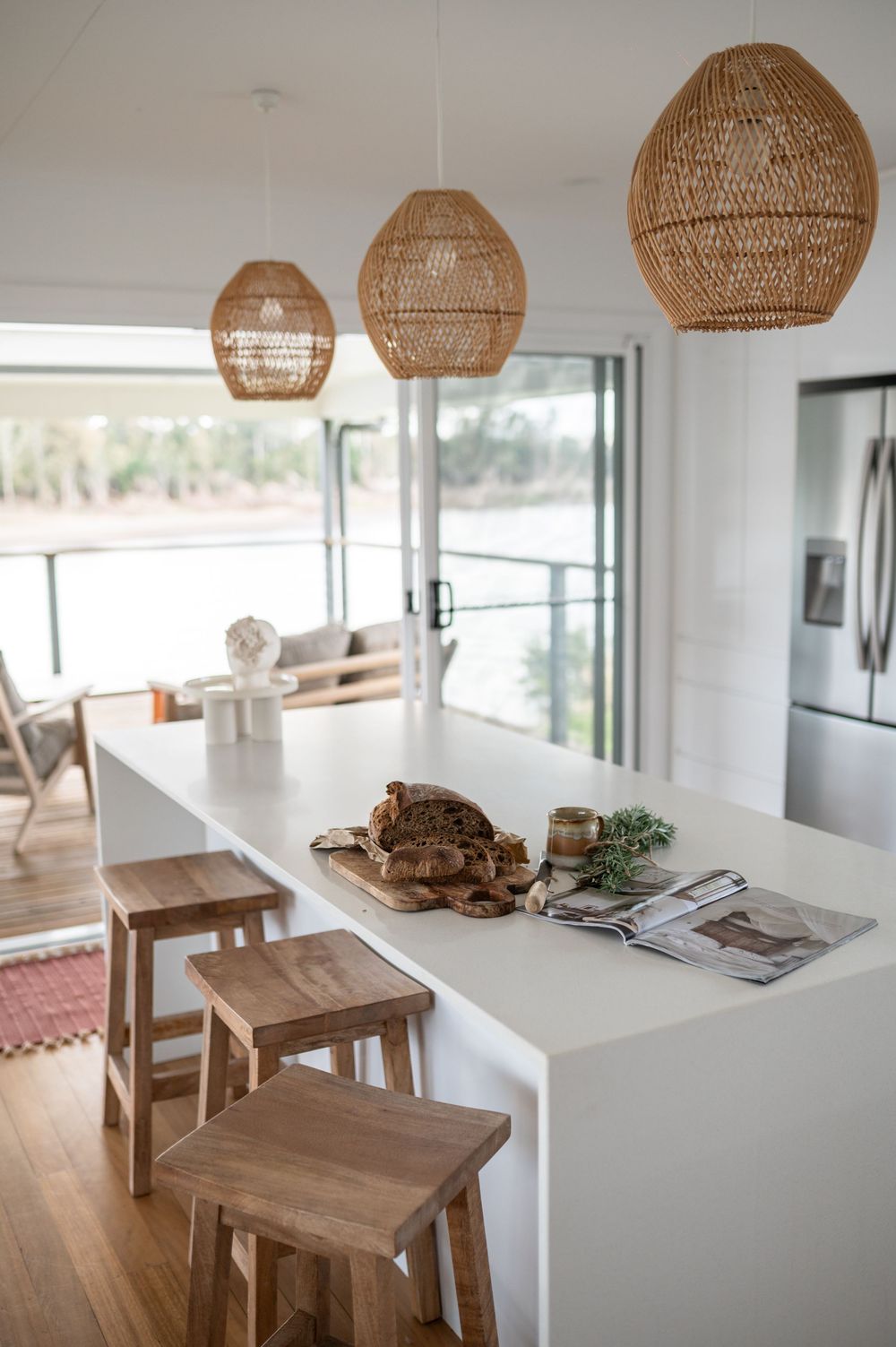 Modern dining area with wooden tables and rattan pendant lights in a bright white minimalist room.