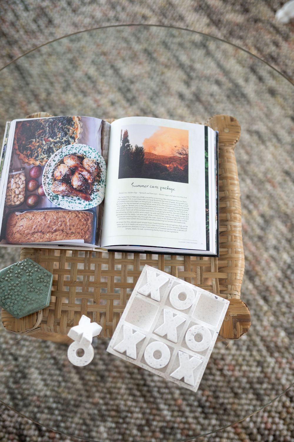 Book spread laying open on woven rattan furniture showing printed photographs and text on glossy pages.