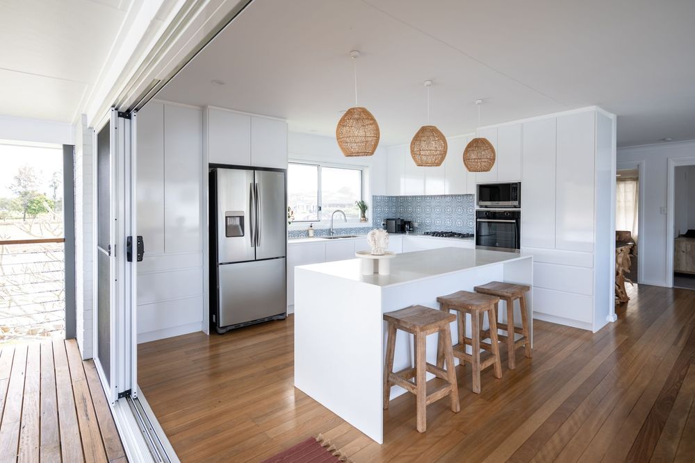 Modern open concept living space with wood floors, white walls, and pendant lighting showcasing a contemporary minimalist design.