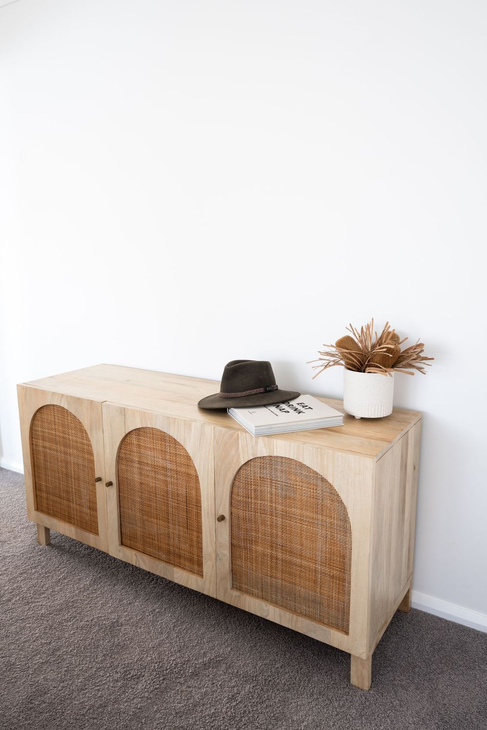 Natural wood storage bench with woven cane panels creates an elegant entryway piece.