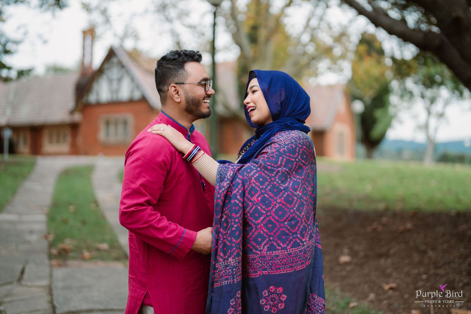 A couple in traditional South Asian attire sharing romantic moments during an outdoor autumn photoshoot.