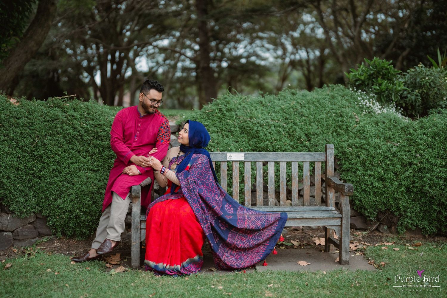 Romantic engagement photos captured in a lush garden with beautiful landscaping and park benches.
