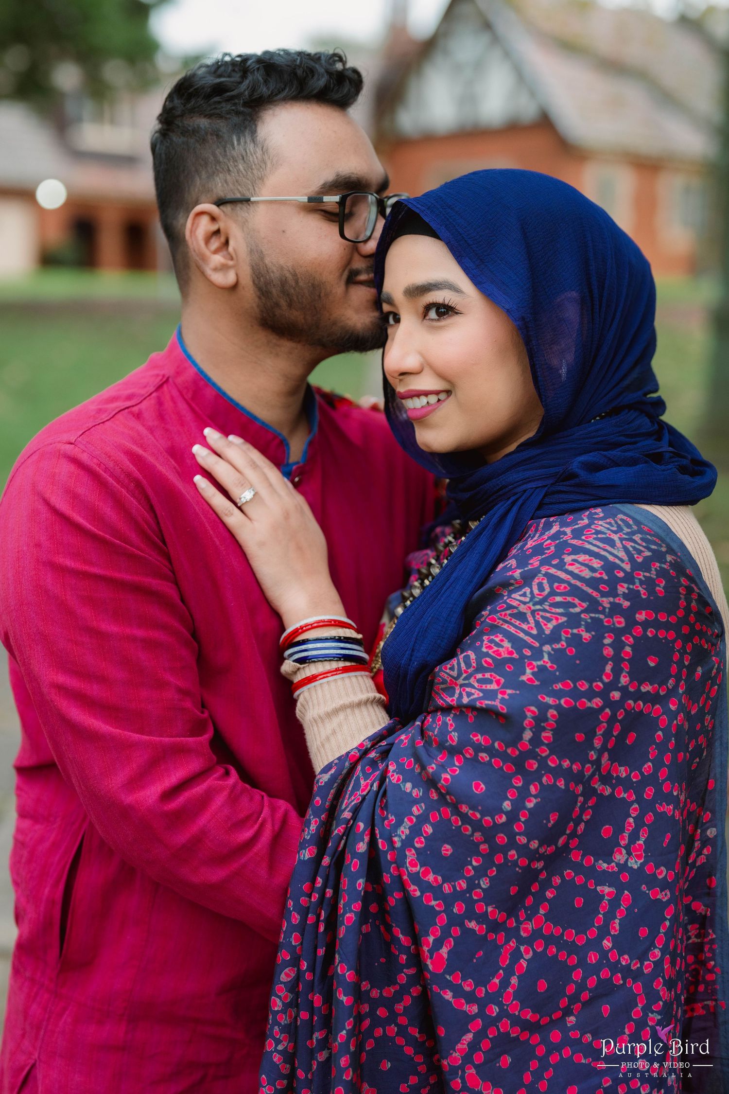 A romantic moment between a couple wearing vibrant red and blue traditional South Asian clothing.