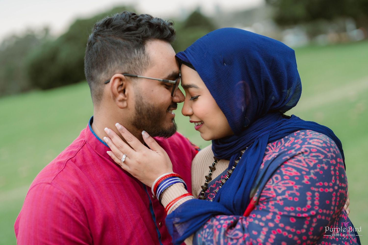 A couple in traditional dress share romantic moments outdoors in a garden setting.