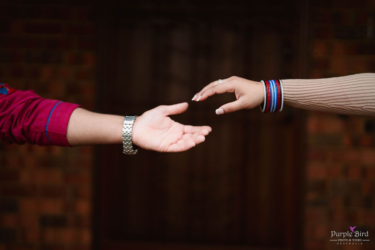 The same couple's hands reach for each other in a romantic gesture on a dark background.