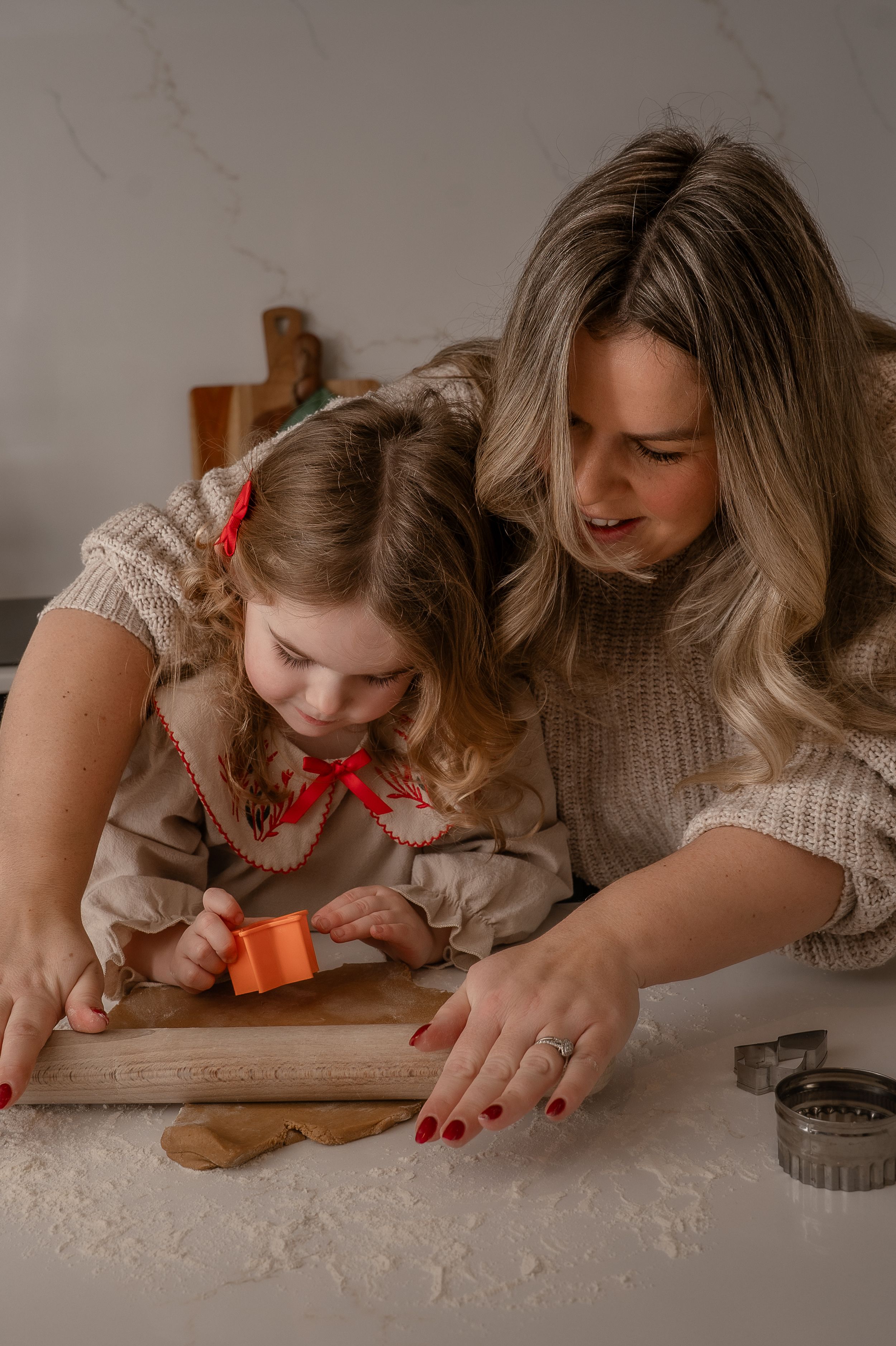 a mum and daughter baking ginger bread cookies with smiles on their faces