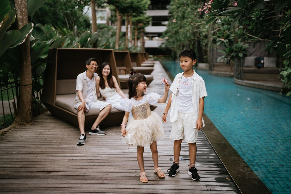 Playful moments captured along wooden deck walkway beside turquoise pool.