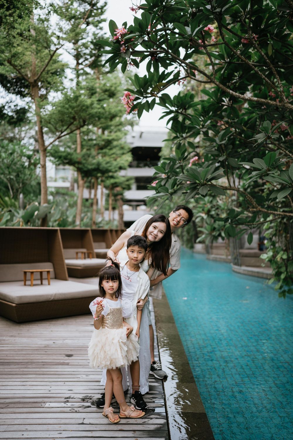 Candid family photos taken on wooden deck with tropical landscaping and pool.