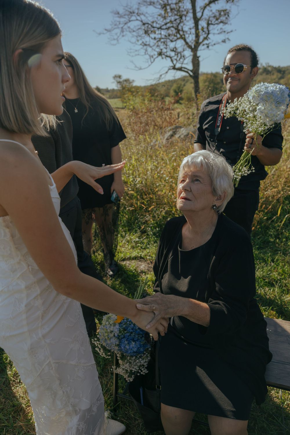 Emotional outdoor wedding scene with guests embracing and sharing joyful moments in a natural setting.
