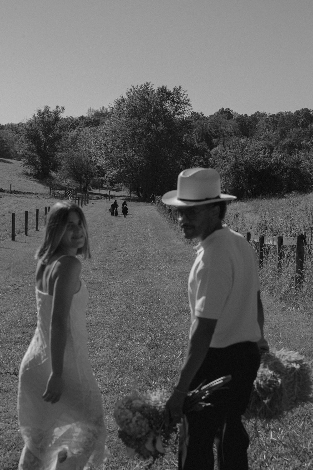 Two people walk together on a grassy path in black and white tones.