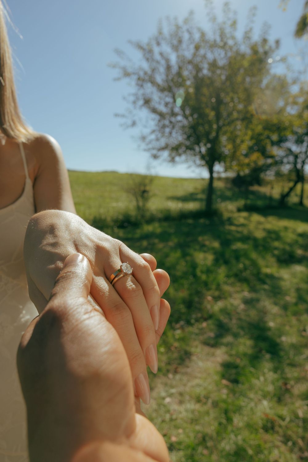 Close-up of two hands clasped together against a sunny outdoor background.
