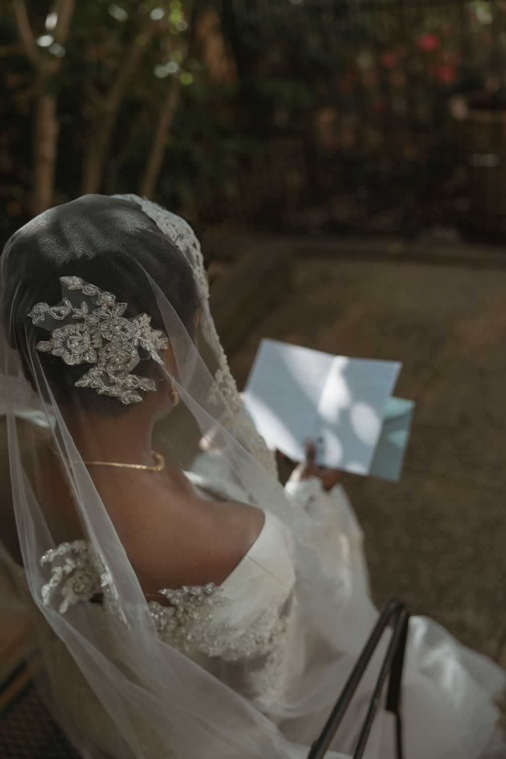 A bride wearing a delicate lace veil and white wedding gown adorned with floral details.