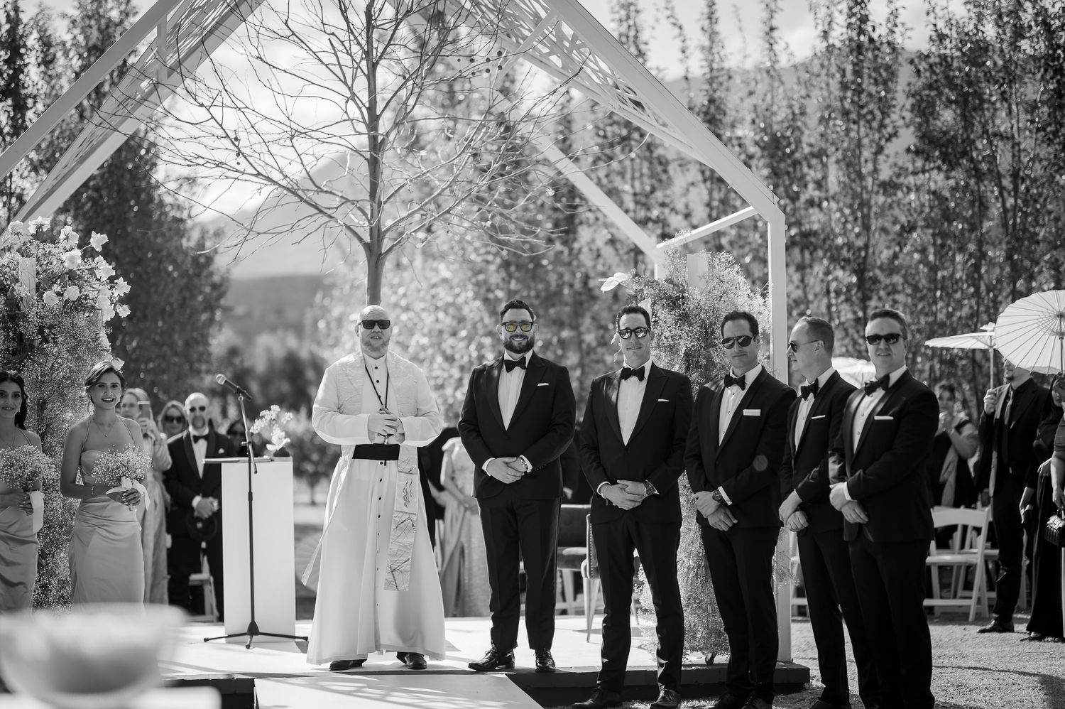 A series of black and white wedding party photos arranged in a panoramic collage showing outdoor ceremony scenes.