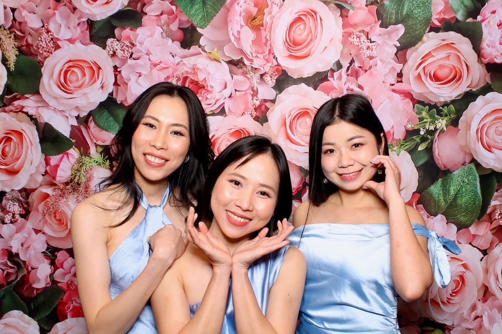 Photo booth strip showing friends having fun posing and smiling in front of a pink floral backdrop.