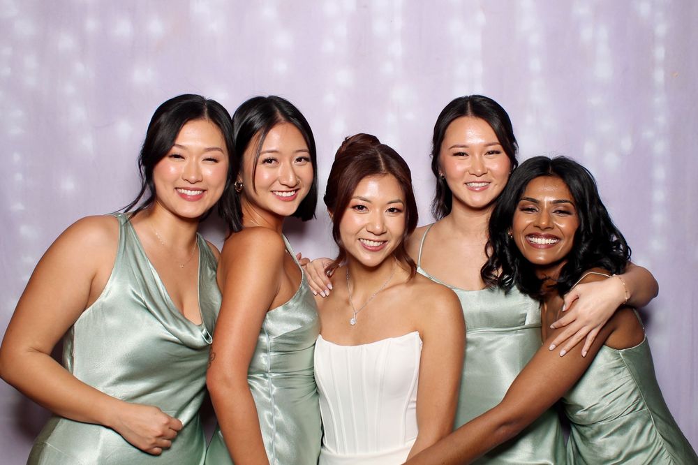 A group of bridesmaids wearing matching mint green dresses pose together for a wedding photo shoot.