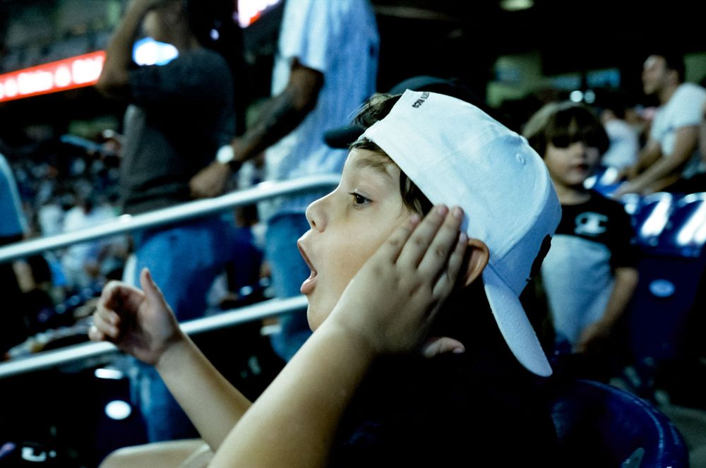 Spectators wearing blue baseball caps watching a game from stadium seats.