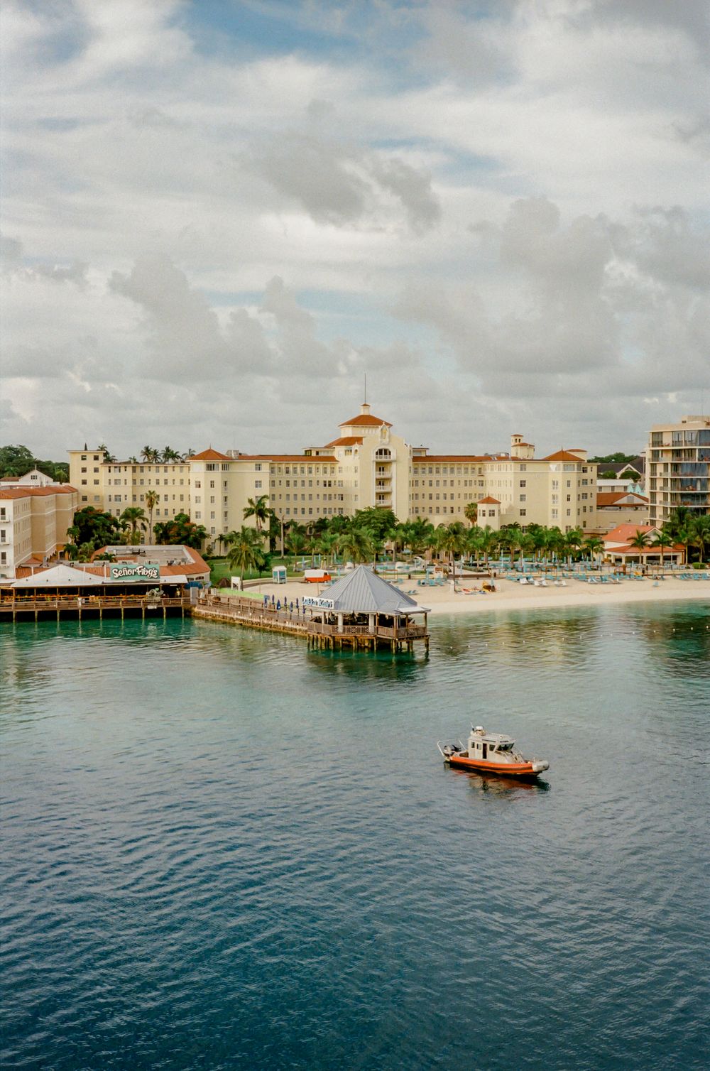 Panoramic view of a tropical Caribbean resort with beachfront buildings and turquoise waters near a wooden pier.