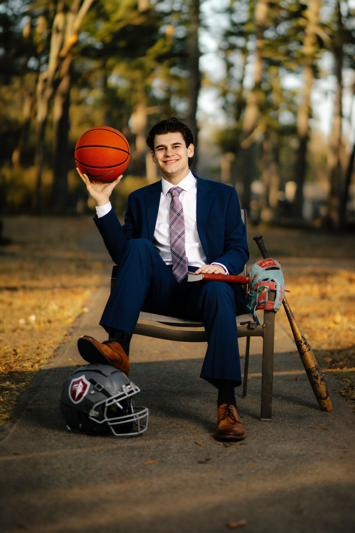Professional seated outdoors with navy suit and tie holding basketball showing progression sequence from left to right.