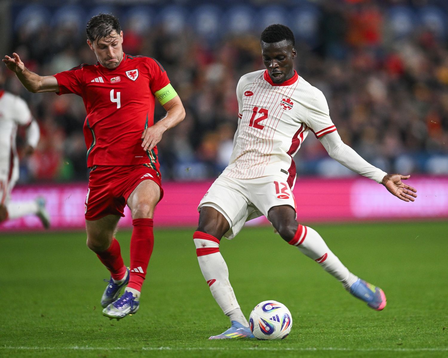 Soccer players compete for the ball during an intense match between teams in red and white uniforms.