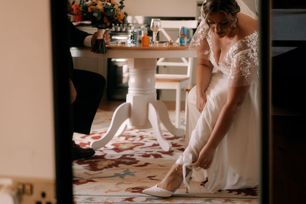 A close up of feet wearing light colored dance shoes and a ruffled white dress during an elegant event.