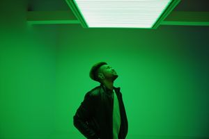 A silhouette dances against a vibrant green light background creating a dramatic artistic effect.