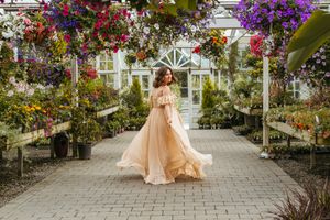 A romantic garden walkway with blooming flowers and greenery creates a stunning backdrop for an elegant peach gown.