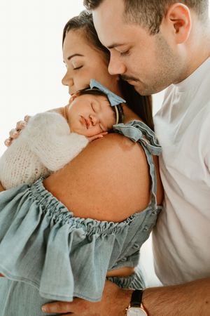 A tender moment captured in a series of intimate photographs showing a couple in soft white and sage green tones.