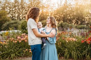 A couple shares tender moments in a garden at sunset surrounded by blooming orange daylilies and golden light.