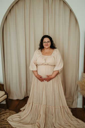 A flowing cream-colored prairie dress with puff sleeves and tiered skirt shown in multiple angles against a beige backdrop.