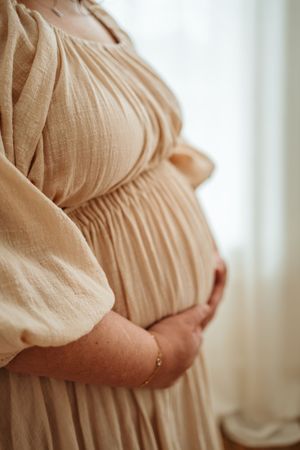 A progression of pregnancy photos showing a growing baby bump in a flowing beige dress against a light background.