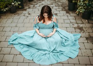 A flowing turquoise dress twirls gracefully across stone pavement in a garden setting.