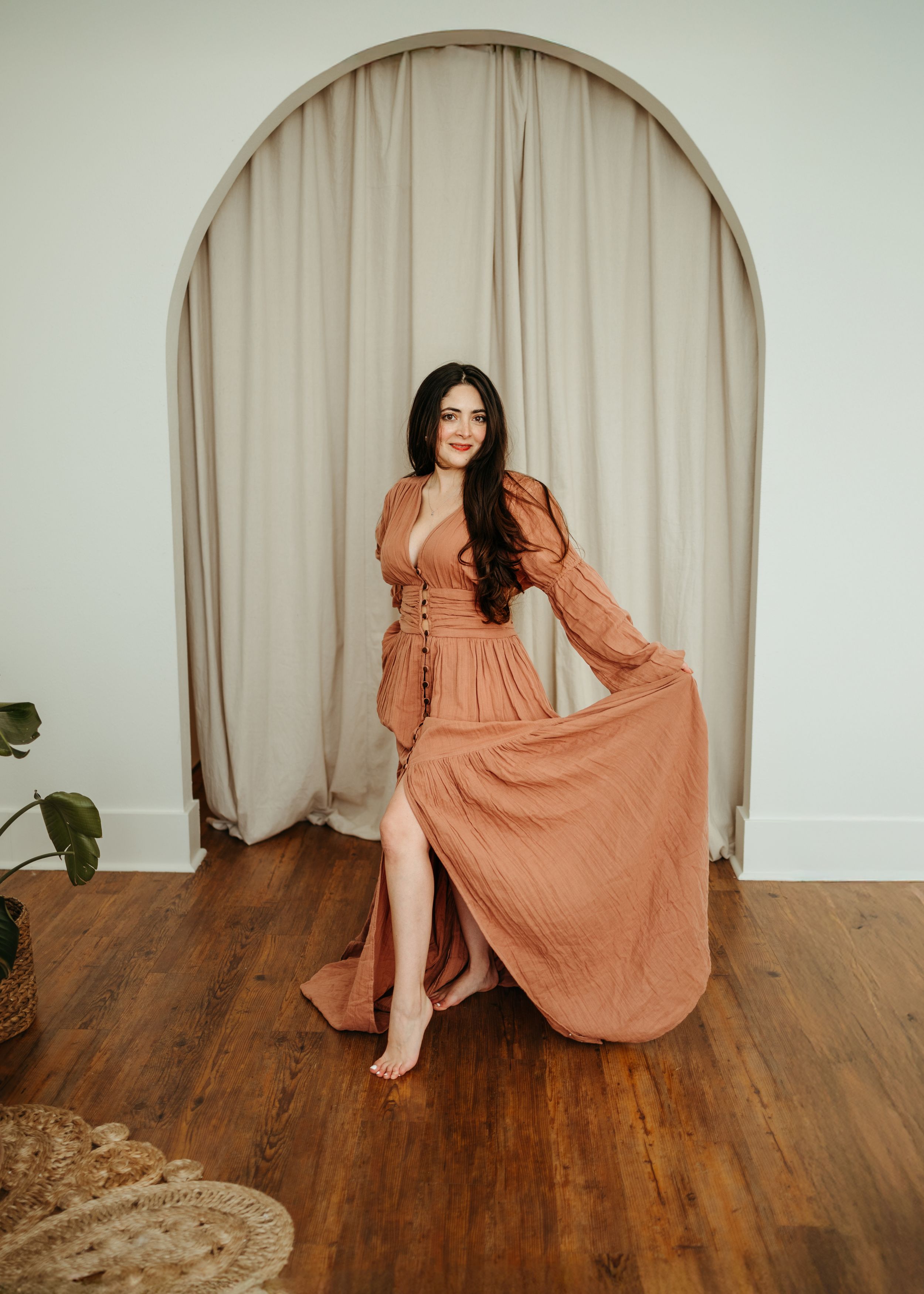 A series of five photos showing a flowy terracotta-colored maxi dress styled on a wooden floor with beige curtains.