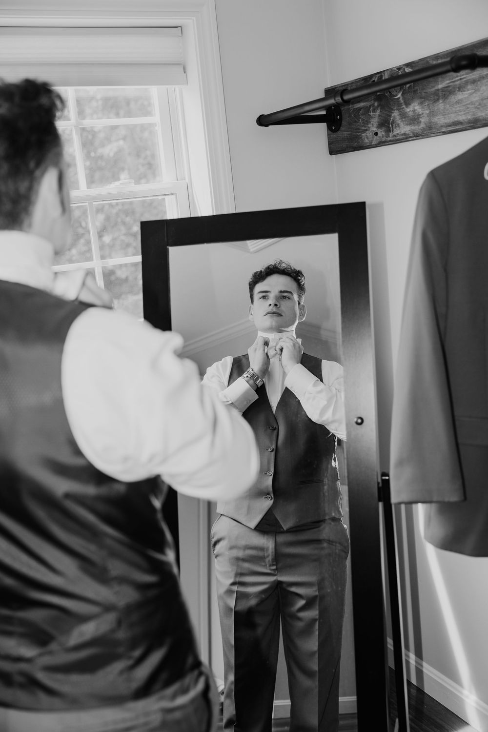 A black and white photo sequence showing someone adjusting their formal attire in front of a window.