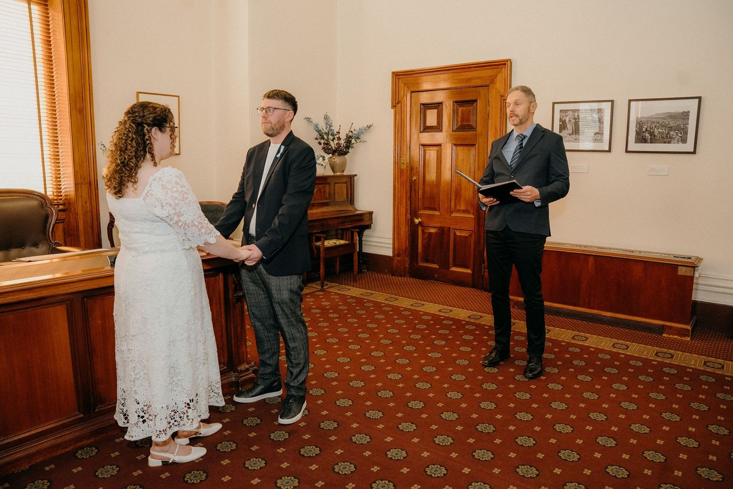 A sequence of five engagement photos showing a couple interacting in a hallway with red carpeting and wooden walls.